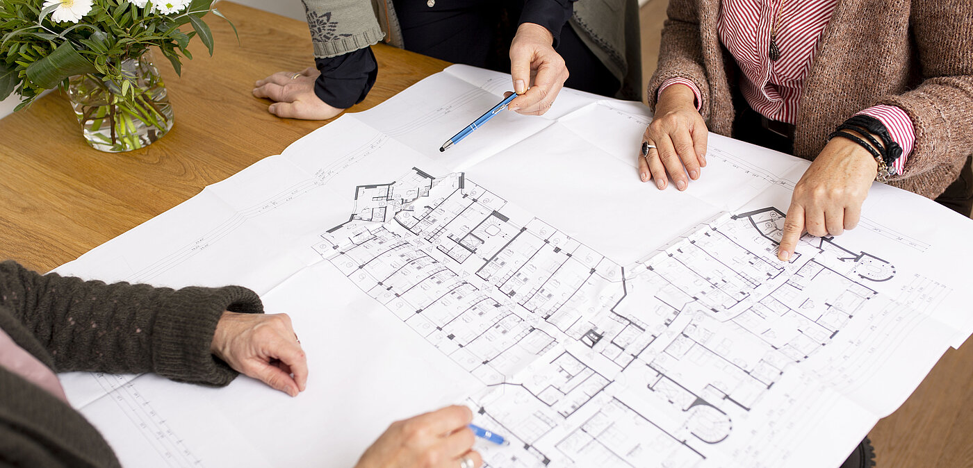 Das Bild zeigt einen Plan und Hände von verschiedenen Personen