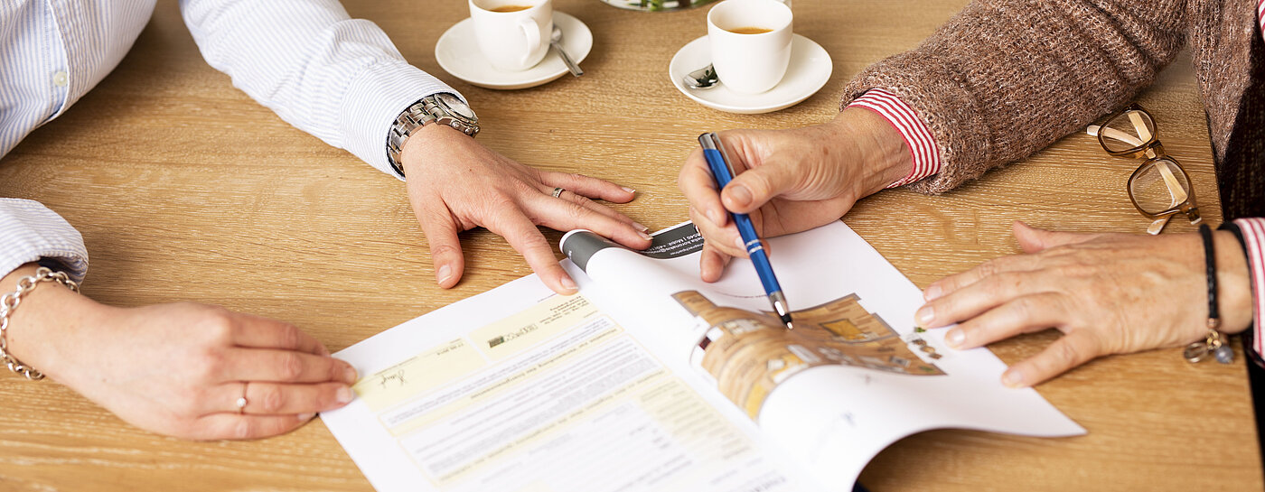 Zu sehen sind der Grundriss einer Wohnung und Hände von zwei Personen