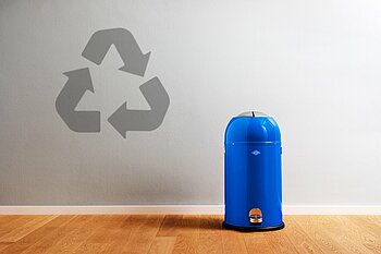 [Translate to Chinesisch:] Blaue Mülltonner vor grauer Wand mit Recyclingsymbol